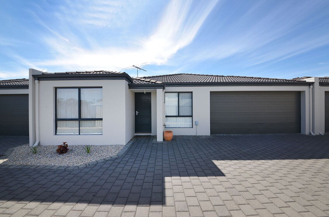 A modern two-story house with a tiled roof, large windows, and a driveway leading to a garage.