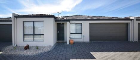 A modern two-story house with a tiled roof, large windows, and a driveway leading to a garage.