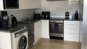 Kompakti keittiö, jossa on pyykinpesukone, mikroaaltouuni, leivänpaahdin, kahvinkeitin ja liesi.