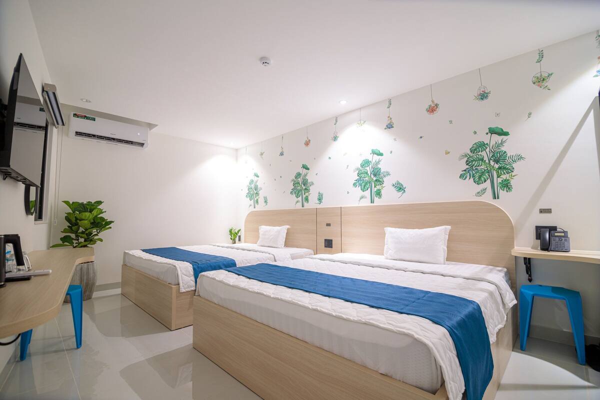 Un dormitorio moderno con dos camas, un escritorio y una planta pequeña.