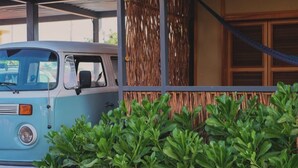 A vintage blue van parked in front of a building with a woven bamboo fence and a hammock. - Elvis Surf Shack at Casa Akaw: a perfect retreat in a sustainable residence (Playa La Saladita)