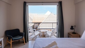 A hotel room with a bed, a chair, a small table, and a balcony with chairs and a table. - Freedom Backpackers Hostel (Rainbow Beach)