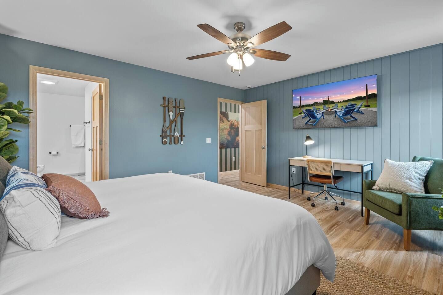 Une chambre à coucher comprenant un lit, un bureau, une chaise et un ventilateur de plafond.