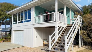 A two-story house with a balcony, a garage, and a staircase leading to the upper level. - Wrightsville Beach Cottage with Stunning Sunset Views, Steps From the Water (Wrightsville Beach)