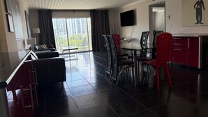 Une chambre d’hôtel moderne dotée d’un coin repas, de grandes fenêtres et d’un téléviseur à écran plat.