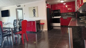 Une cuisine moderne avec des meubles rouges, un réfrigérateur noir et un four à micro-ondes.