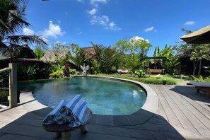 Ein Schwimmbad mit Liegestühlen und einer Holzterrasse.