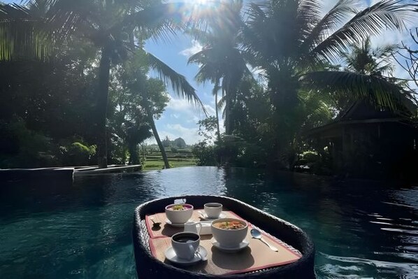 Un bateau avec une table dressée pour un repas, entouré d’eau et de palmiers.