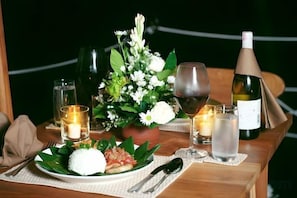 Een gedekte tafel met eten, wijnkansen, een kaars en een fles wijn.
