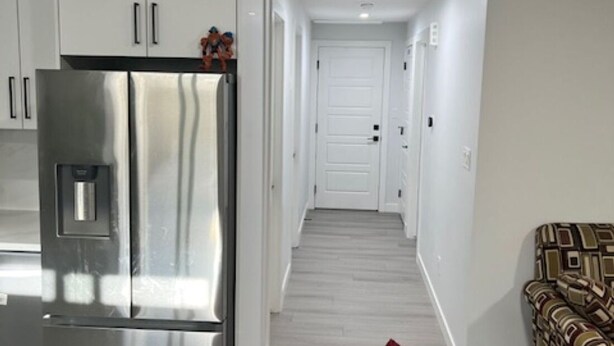 Una cocina moderna con armarios blancos y un refrigerador de acero inoxidable.