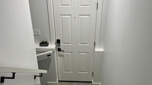 Una escalera que lleva a una puerta blanca con una planta pequeña en el rellano.
