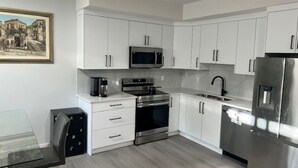Una cocina moderna con armarios blancos, electrodomésticos de acero inoxidable y una mesa de vidrio.