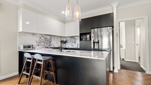 A modern kitchen with a marble backsplash, stainless steel appliances, and a central island with bar stools. - Cozy Retreat with Modern Comforts (Entire place) (Camp Hill)