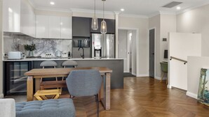 A modern kitchen with white cabinets, a marble backsplash, and a wooden dining table with chairs. - Cozy Retreat with Modern Comforts (Entire place) (Camp Hill)