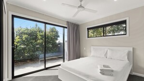 A modern bedroom with a large bed, a ceiling fan, and a view of greenery outside. - Cozy Retreat with Modern Comforts (Entire place) (Camp Hill)
