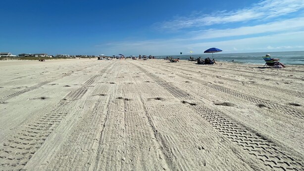 A wide sandy beach with footprints and tire tracks, umbrellas, and people relaxing. - 3-bdrm in Ship Bottom. 2 blocks from beach and bars. Surfboards included! (Ship Bottom)