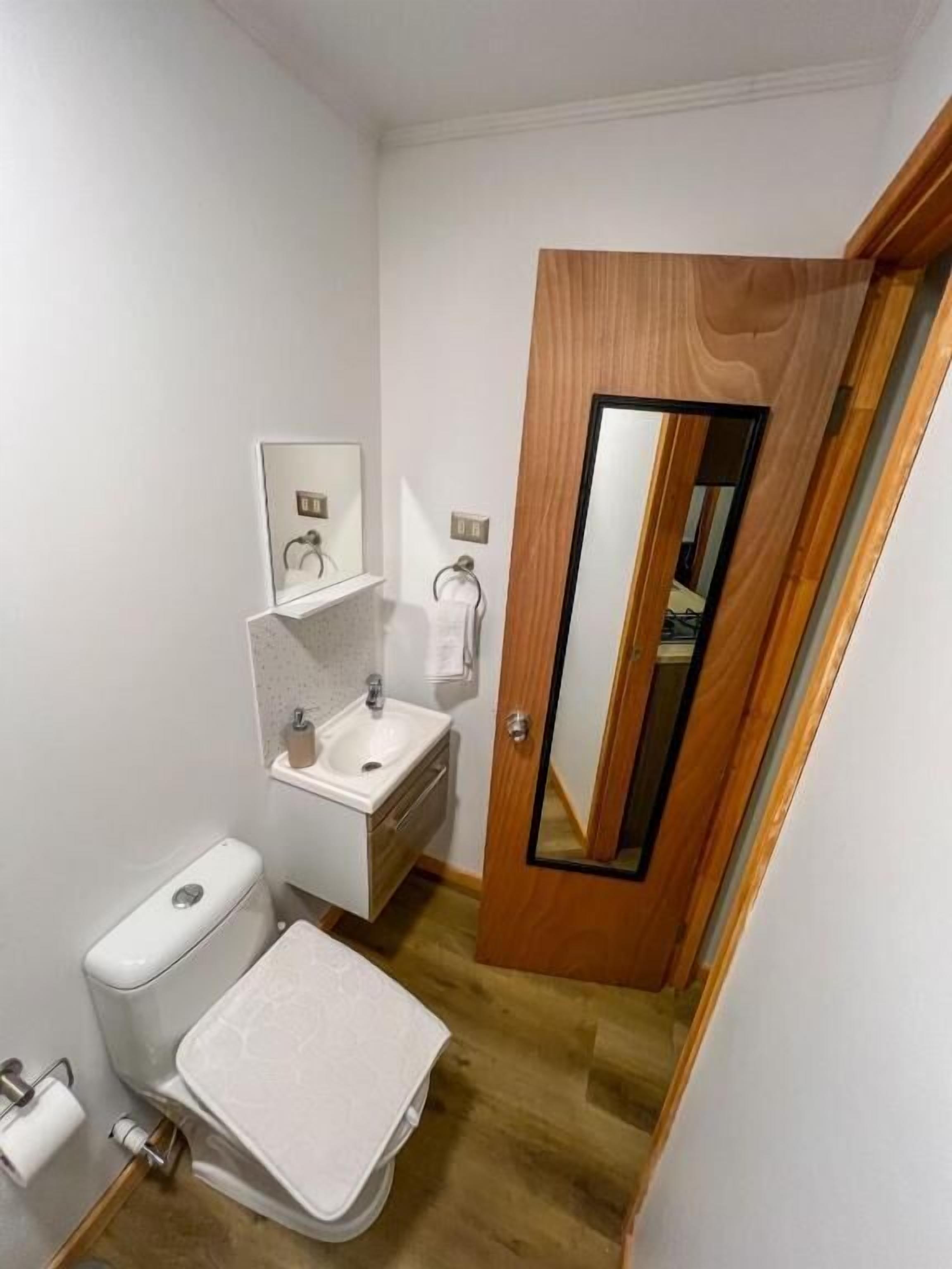 A compact bathroom with a toilet, sink, and mirror.