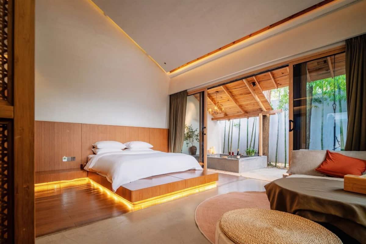 Un dormitorio moderno con una cama grande, un sofá y vistas a bambú.