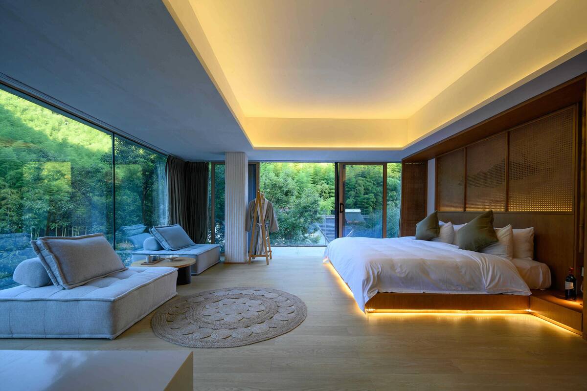 Un dormitorio moderno con una cama grande, una zona de estar y vistas al exterior.