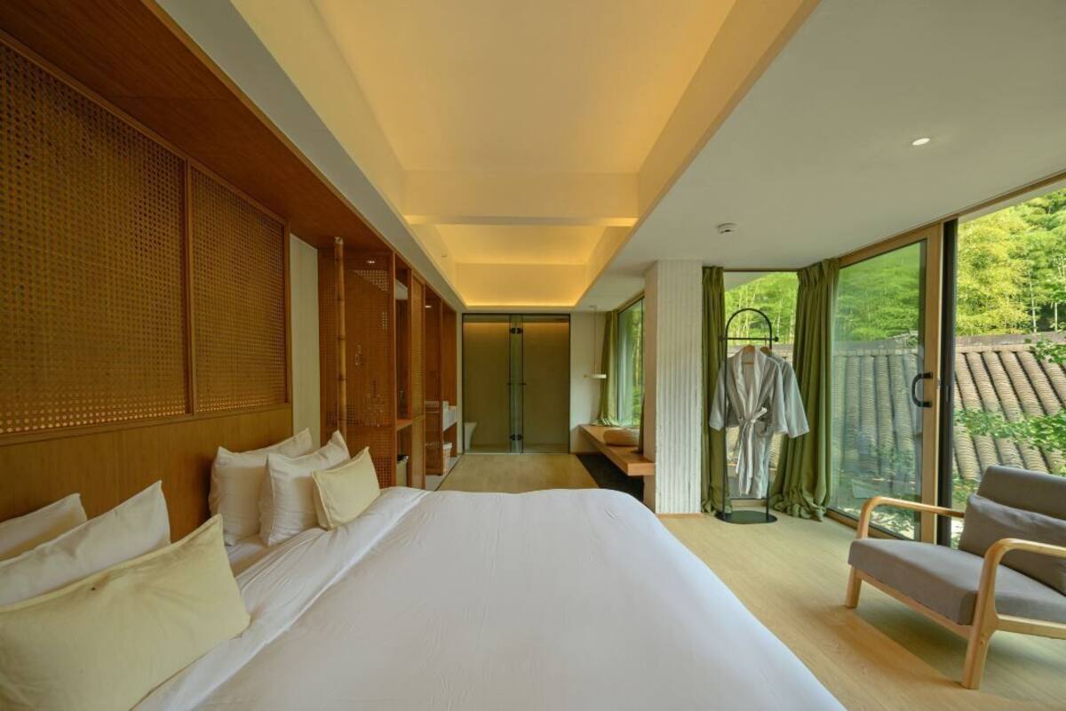 Habitación de hotel con una cama grande, zona de estar y vistas al exterior.