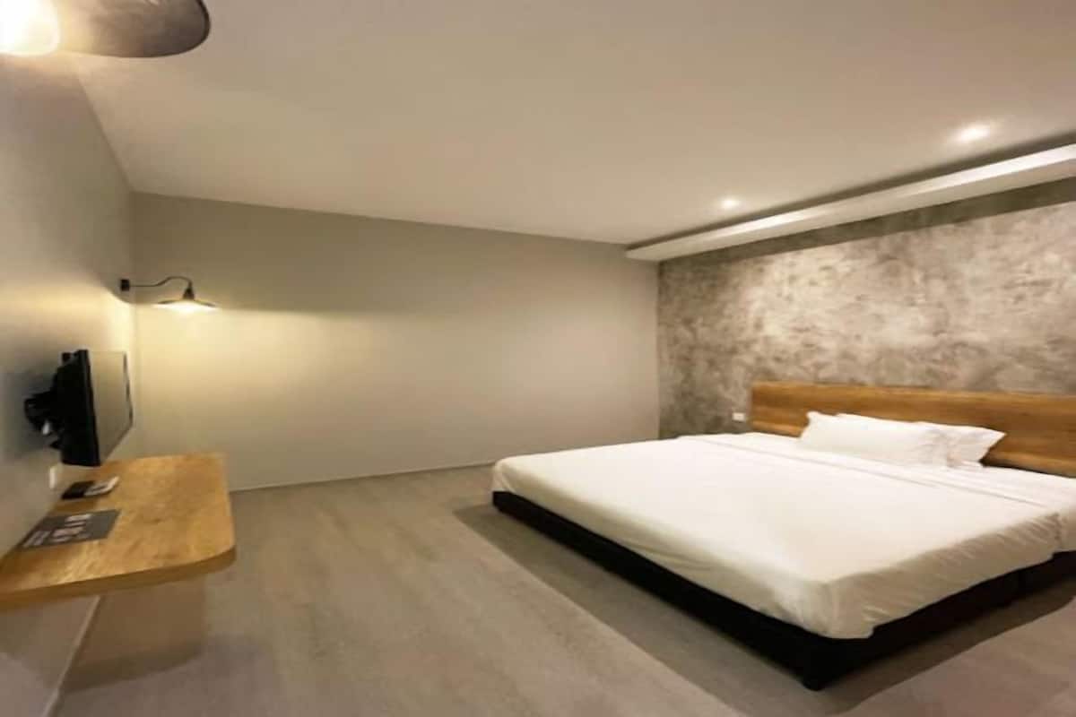 A modern bedroom with a single bed, a wooden headboard, a bedside table, and a wall-mounted TV.