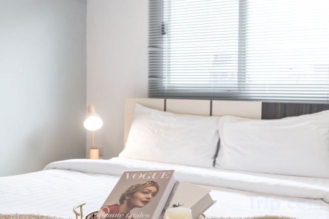 A bedroom with a bed, a bedside table, a lamp, and a magazine on the bed.