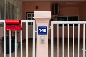 Una entrada protegida por una verja con un buzón y un cartel con un número.
