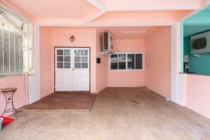 Una habitación con suelo de madera, una puerta blanca, un ventanal con persianas y una pared color turquesa.