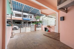 Un espacio al aire libre cubierto con piso de baldosas, una reja metálica y un edificio de fondo.