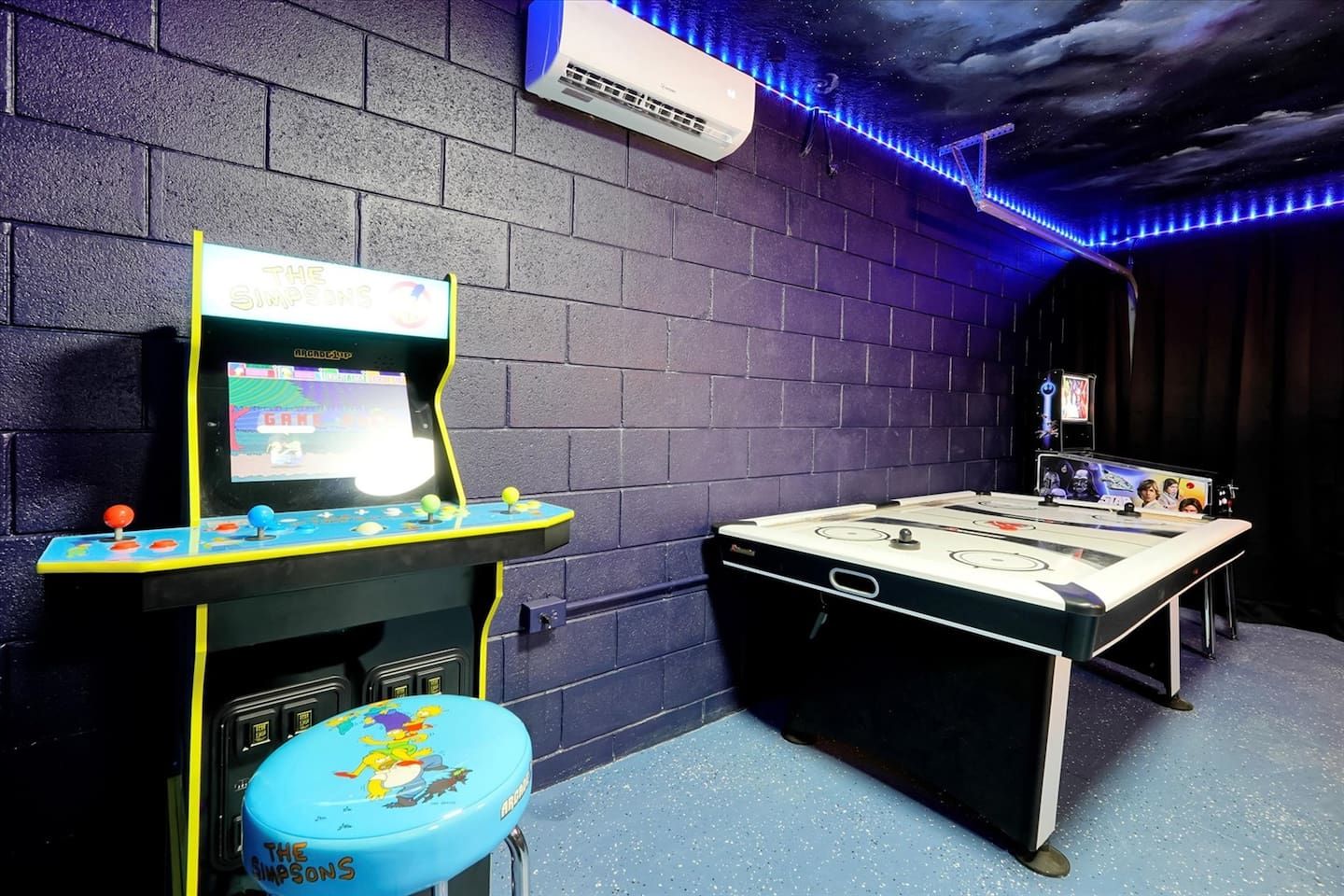 Une pièce équipée d’une table de jeux, d’une console de jeux et d’un climatiseur fixé au mur.