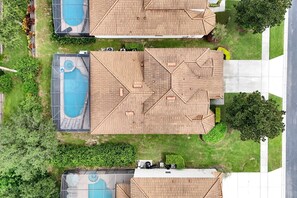 A residential area with two houses, each featuring a swimming pool and a wooden roof.