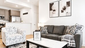A modern living room with a sofa, armchair, and a framed sign indicating a rental guestbook.