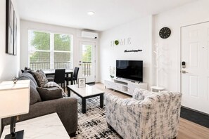 Un salon moderne avec un canapé, une table basse et un téléviseur à écran plat.