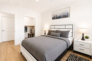 Ein Schlafzimmer mit Bett, Nachttischen, einem Schrank und einem Gemälde.