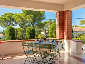 Una terraza con mesa lista para comer, rodeada de vegetación y una chimenea de ladrillo.
