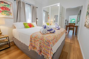 A hotel room with a bed, a bedside table, a lamp, a colorful blanket, and a mirror.