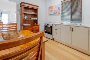 A kitchen with wooden cabinets, a stove, and a dining table with chairs.