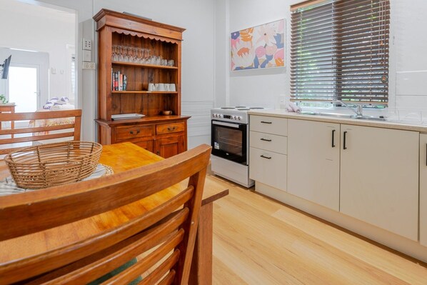 A kitchen with wooden cabinets, a stove, and a dining table with chairs.