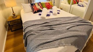 Et hotelværelse med en seng, et natbord, en lampe, et spejl og en væg med et fiskemotiv.