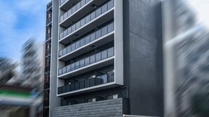 A modern multi-story building with a flat facade, large windows, and a prominent entrance. - Apartment Hotel 11 Dotonbori 7 (Osaka)