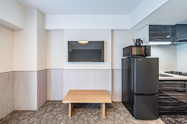 A compact kitchen with a built-in microwave, a refrigerator, and a small wooden table.