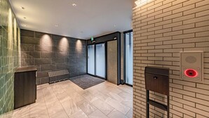 A modern lobby with a tiled floor, a reception desk, and a wall-mounted intercom system. - Apartment Hotel 11 Dotonbori 7 (Osaka)