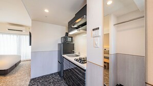 A compact hotel room with a kitchenette, a bed, and a bathroom. - Apartment Hotel 11 Dotonbori 7 (Osaka)