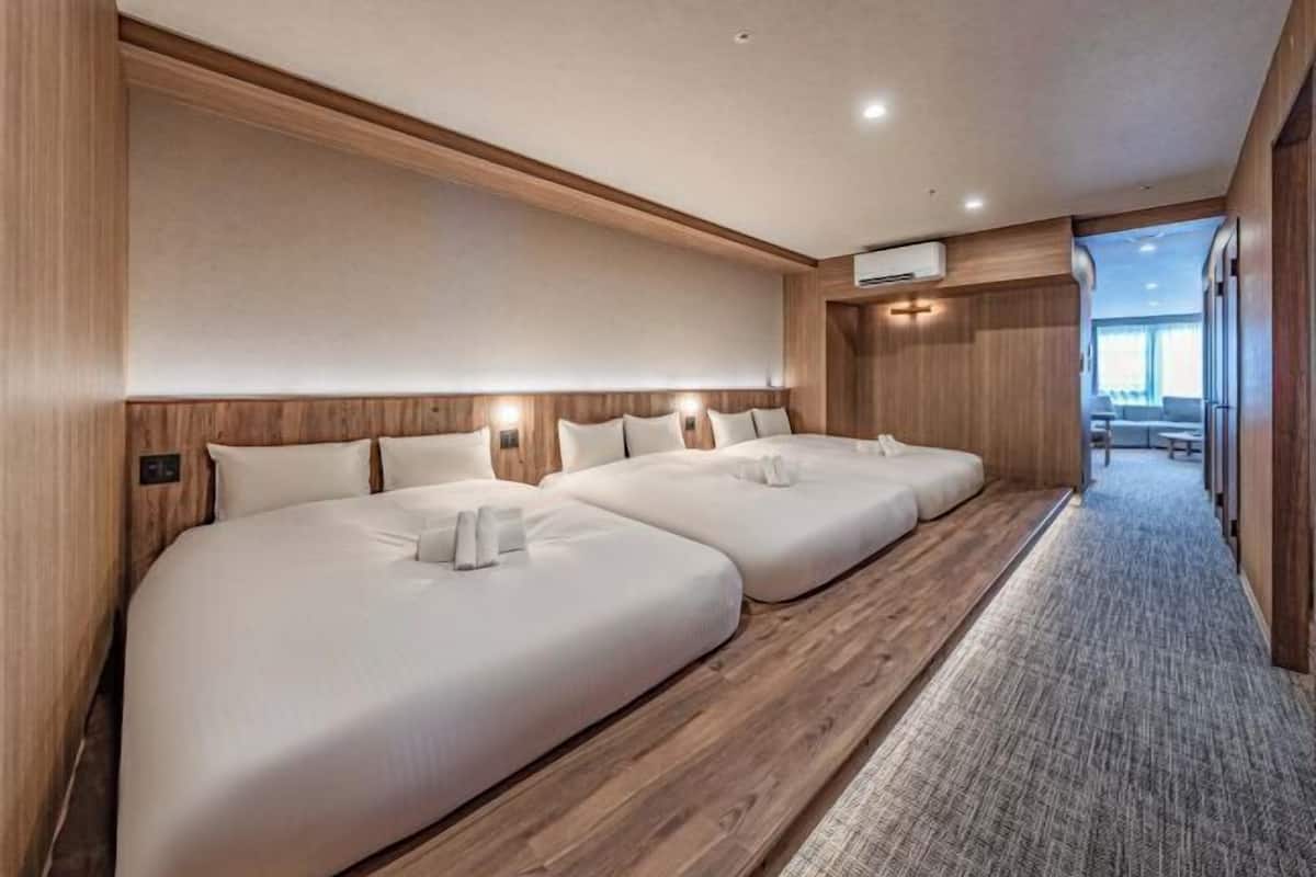 Une chambre d’hôtel avec trois lits, des lambris en bois et un sol recouvert de moquette.