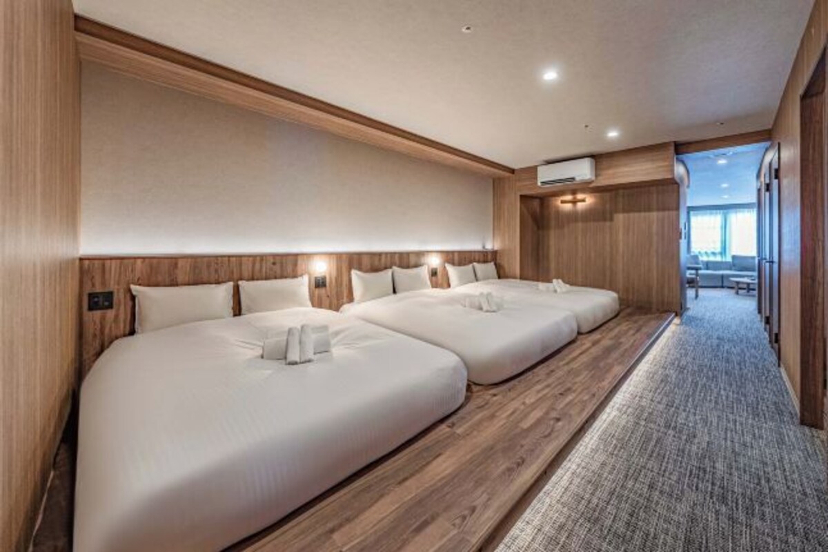 A hotel room with three beds, wooden paneling, and a carpeted floor.