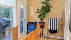 A wooden staircase with a railing, a large potted plant, a striped towel, and a coat rack. - Waterfront Comfy Guesthouse, Prince Edward County (Carrying Place)