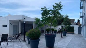 A courtyard with potted plants, outdoor seating, and a modern building facade.