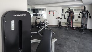 A gym with various exercise equipment, including a weight bench, a treadmill, and a stationary bike.