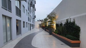 A modern building with a curved pathway, large windows, and potted plants along the walkway.
