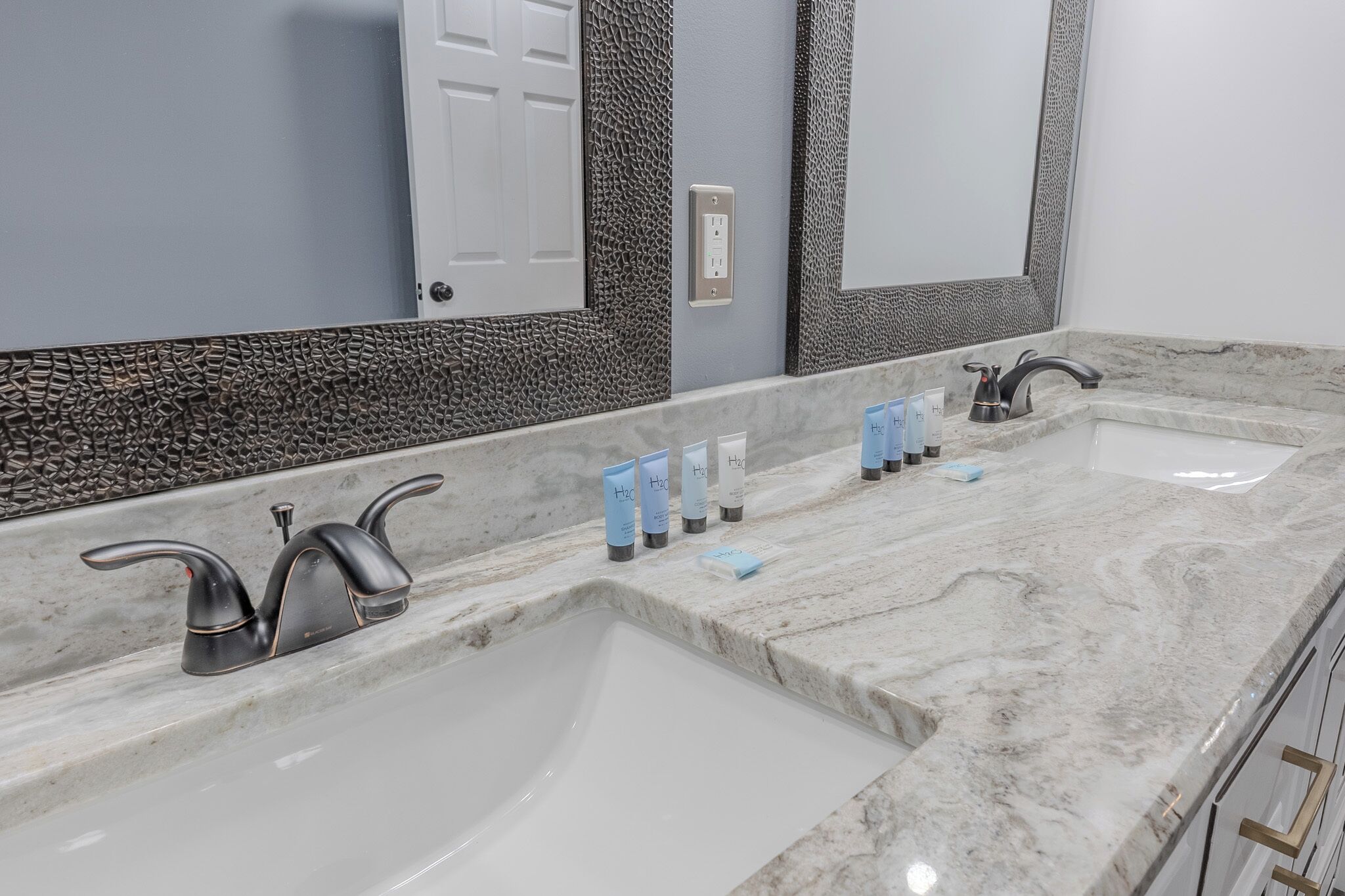 A bathroom with two sinks, marble countertops, and a large mirror.